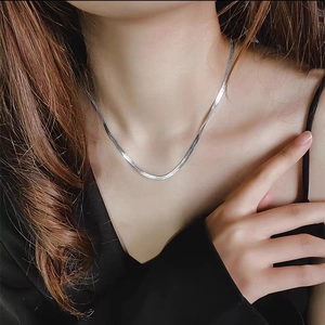 Minimalist silver snake chain necklace worn by a model on a sleek black outfit