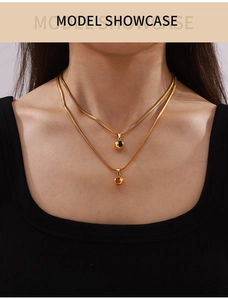 Detail of layered gold snake chain necklace with blue and amber zircon spherical pendants