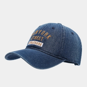 Detailed close-up of yellow New York embroidery on a dark blue denim baseball cap
