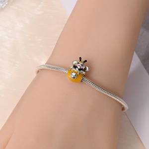 Close-up of silver bee charm with yellow enamel and HONEY engraving on snake chain bracelet