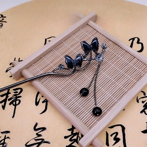Detail of metal butterfly hair stick with tassels on bamboo mat and calligraphy paper