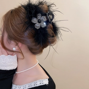Détail d'une pince à cheveux de luxe avec plumes noires et fleur en strass brillants