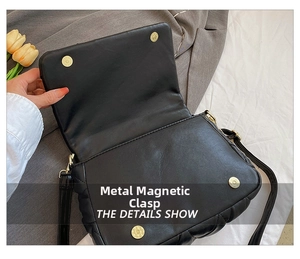 Detail of the golden magnetic buckle closure on a black quilted leather crossbody bag