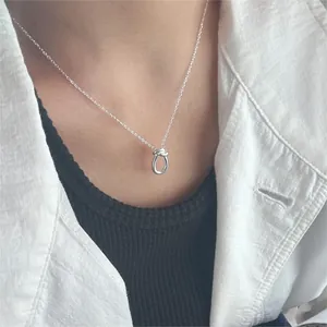 Close-up of a 925 sterling silver knotted pendant necklace worn on a female model