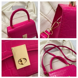 Detail of magenta faux crocodile skin handbag with gold metal lock and braided handle