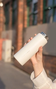 Close-up of matte cream-colored stainless steel insulated bottle with sleek metallic lid