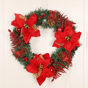 Christmas wreath with red poinsettias and pine cones hanging on a white wooden door