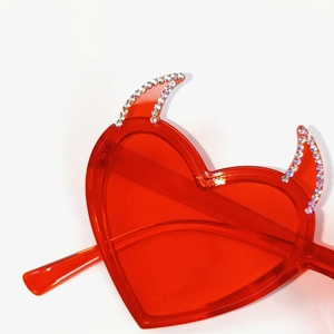 Detail of red heart sunglasses featuring devil horns and silver rhinestone embellishments