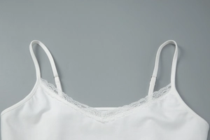 Close-up of white lace trim neckline and adjustable thin straps on a knit camisole