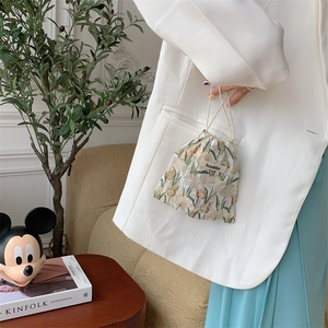 Detail view of floral drawstring pouch with tulip print and woven handle held by model