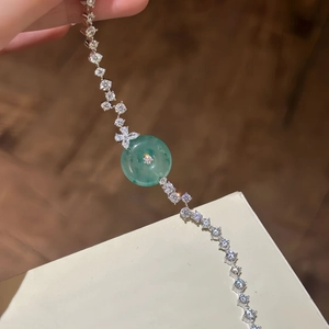 Dettaglio del bracciale in zircone scintillante con ciondolo in calcedonio verde al polso