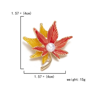 Macro detail of enamel maple leaf brooch with gradient colors and center pearl detail