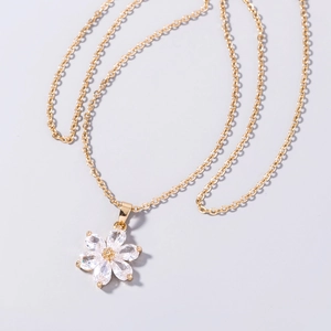 Macro shot of gold flower pendant with clear zircon crystals on minimalist chain