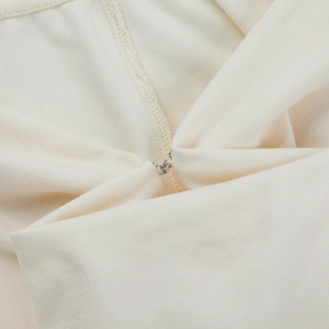 Gros plan du fermoir en métal et de la texture en maille fine sur la robe licou crème
