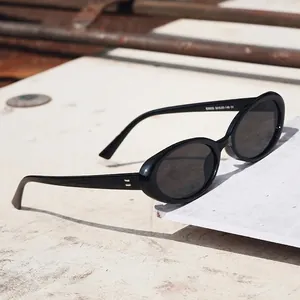Retro black oval sunglasses with UV protection lenses on white stone for women