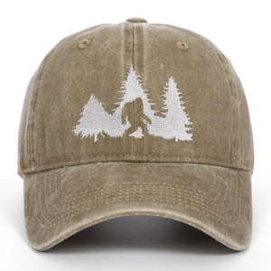Close-up of Bigfoot and pine forest white embroidery on washed brown cotton baseball cap