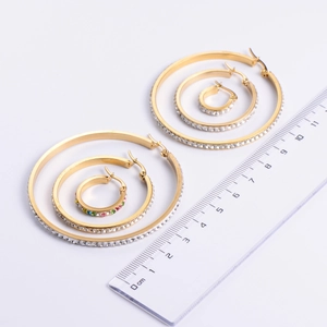 Three-piece gold hoop earrings set with zircon stones in various sizes shown on scale