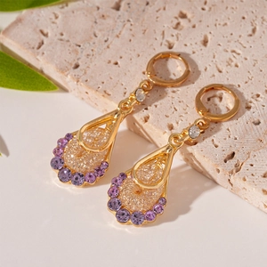 Detailed close-up of water drop earrings with mesh metalwork and purple crystal on stone