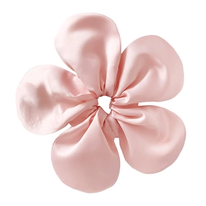 Macro shot of oversized pink satin floral scrunchie with smooth silk texture