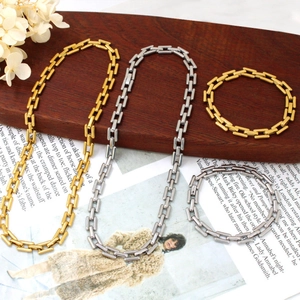 Macro detail of industrial style square link chain necklace and bracelet in gold and silver