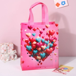 Detail of pink non-woven gift bag with heart pattern and reinforced handles for Valentine