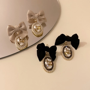 Detail of French vintage bow earrings with pearls and rhinestones on a mirror surface
