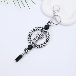 Detail of leopard print silicone keychain with cross charm and black leather tassel