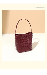 Gros plan sur la texture en cuir PU tressé d'un mini sac seau rouge foncé