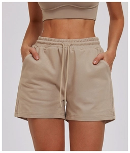 Detail of high-waisted beige knit sports shorts featuring drawstring and side pockets