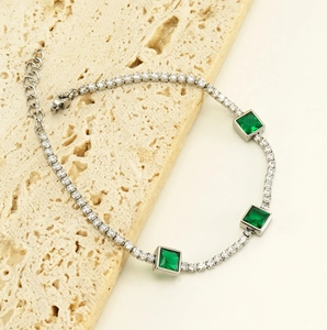 Detailed view of silver tennis bracelet with emerald green square stones and lobster clasp