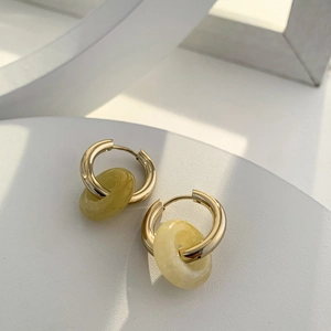 Detail of 18K gold earrings with translucent light green natural stone hoops on white props