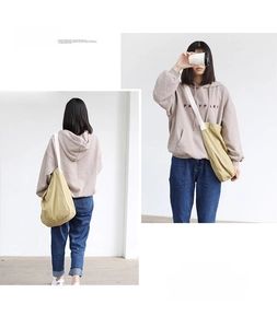 Detail of minimalist khaki canvas shoulder bag with contrast woven strap on model