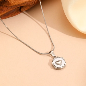 Macro shot of silver stainless steel heart pendant necklace on silk fabric and wood background