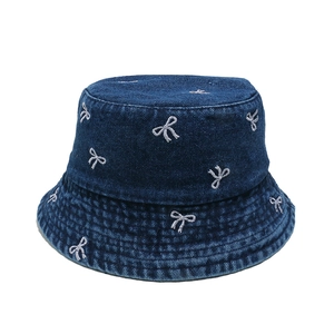 Detail of dark blue denim sun hat with white bow embroidery and washed finish