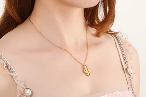 Close-up of golden necklace with Roman numeral plate and crystals on model's neckline