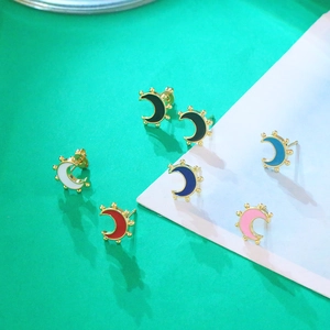 Macro view of 18K gold crescent moon stud earrings with colorful enamel dripping finish