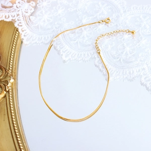 Gold plated square snake chain anklet displayed on a vintage mirror with white lace decor