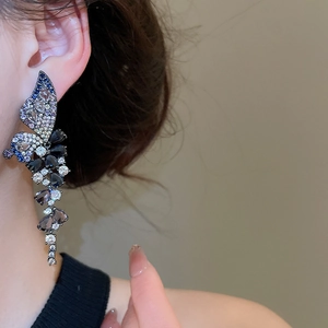Detailed close-up of butterfly drop earrings featuring blue and black zircon tassels