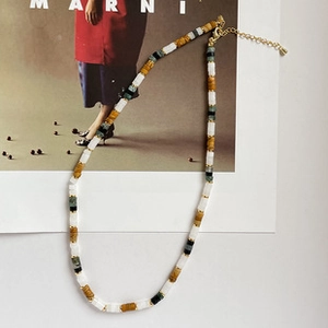 Macro shot of colorful cylindrical beads necklace with gold metal spacers and lobster clasp