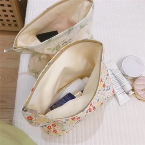 Floral fabric makeup bags with metal zipper on a bed showing storage capacity