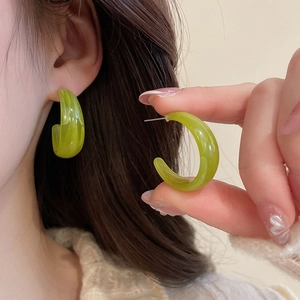 Close-up of C-shaped resin earrings with lime green marble pattern and silver needles