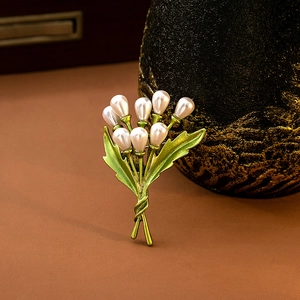 Detailed close-up of golden leaf brooch with elegant white pearls on vintage background