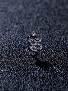 Macro shot of punk style black snake-shaped nose ring with sparkling white cubic zirconia