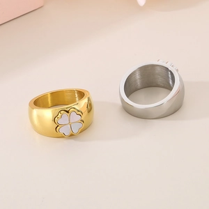 Macro view of gold and silver four-leaf clover rings with white shell inlay details