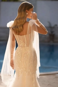 Dettaglio di abito da sposa a sirena con ricami in pizzo e corsetto trasparente sul retro