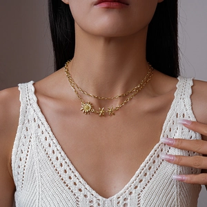 Détail d'un collier doré double couche avec pendentifs tournesol et fleurs sur un cou