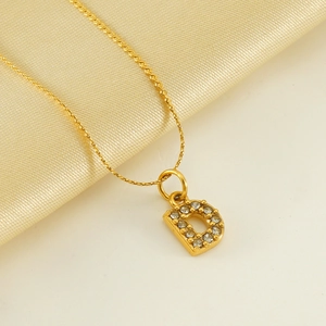 Collana dorata in acciaio con lettera D e diamanti su elegante sfondo in seta