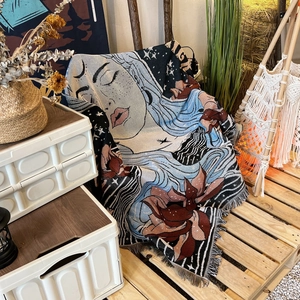 Detail of bohemian woven throw blanket with fringe edges and artistic portrait pattern