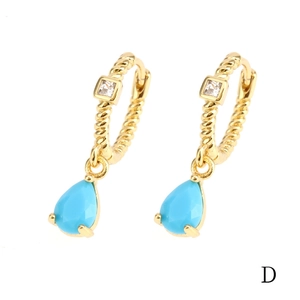 Macro detail of 18K gold hoop earrings with blue pear-cut stone and square zircon