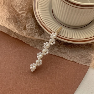 Detail of vintage gold pearl hair clip on retro background with elegant coffee cup